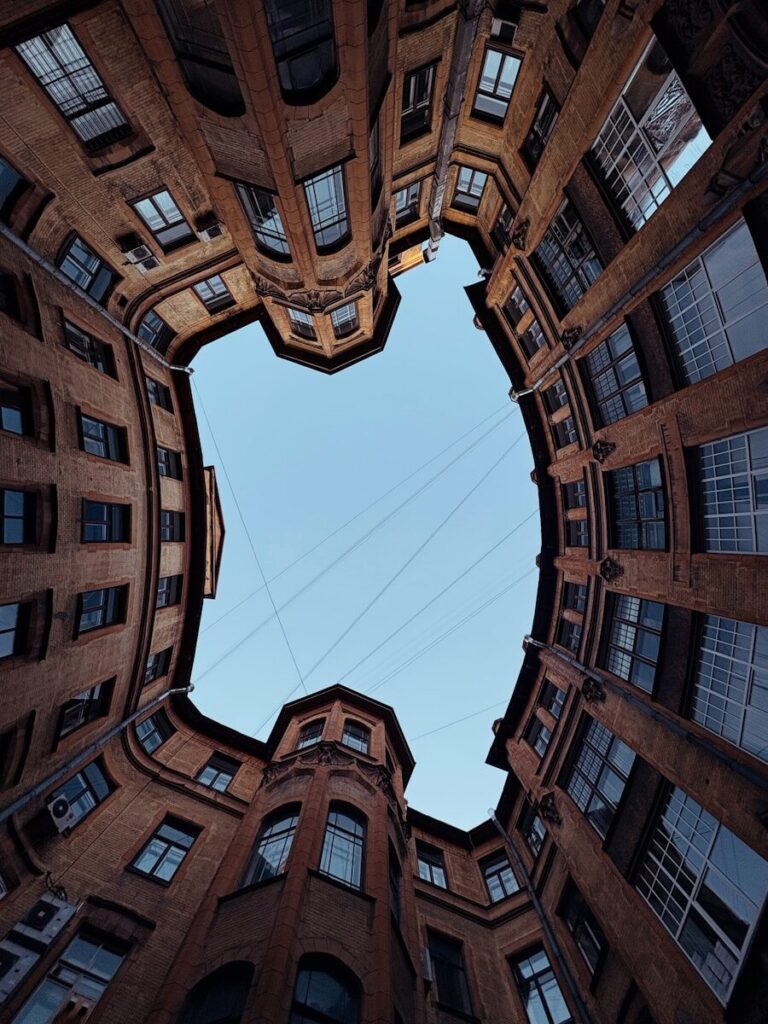 Looking up at old brick buildings forming a heart-shaped sky.